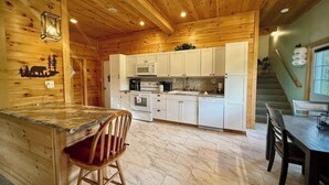Ein Holzblockhaus-Innenraum mit Küche, Essbereich und einer Treppe.