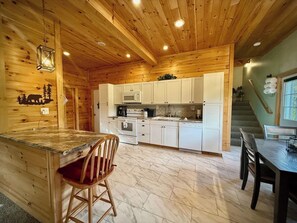 L’intérieur d’un chalet en bois comprend une cuisine, un coin repas et un escalier.
