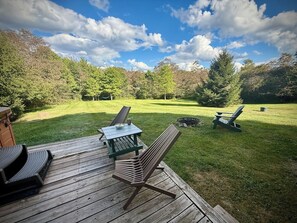 A deck with outdoor furniture, a fire pit, and a grassy area with trees. - Fernwood | Secluded | Deep Creek & Wisp | Hot Tub (Accident)