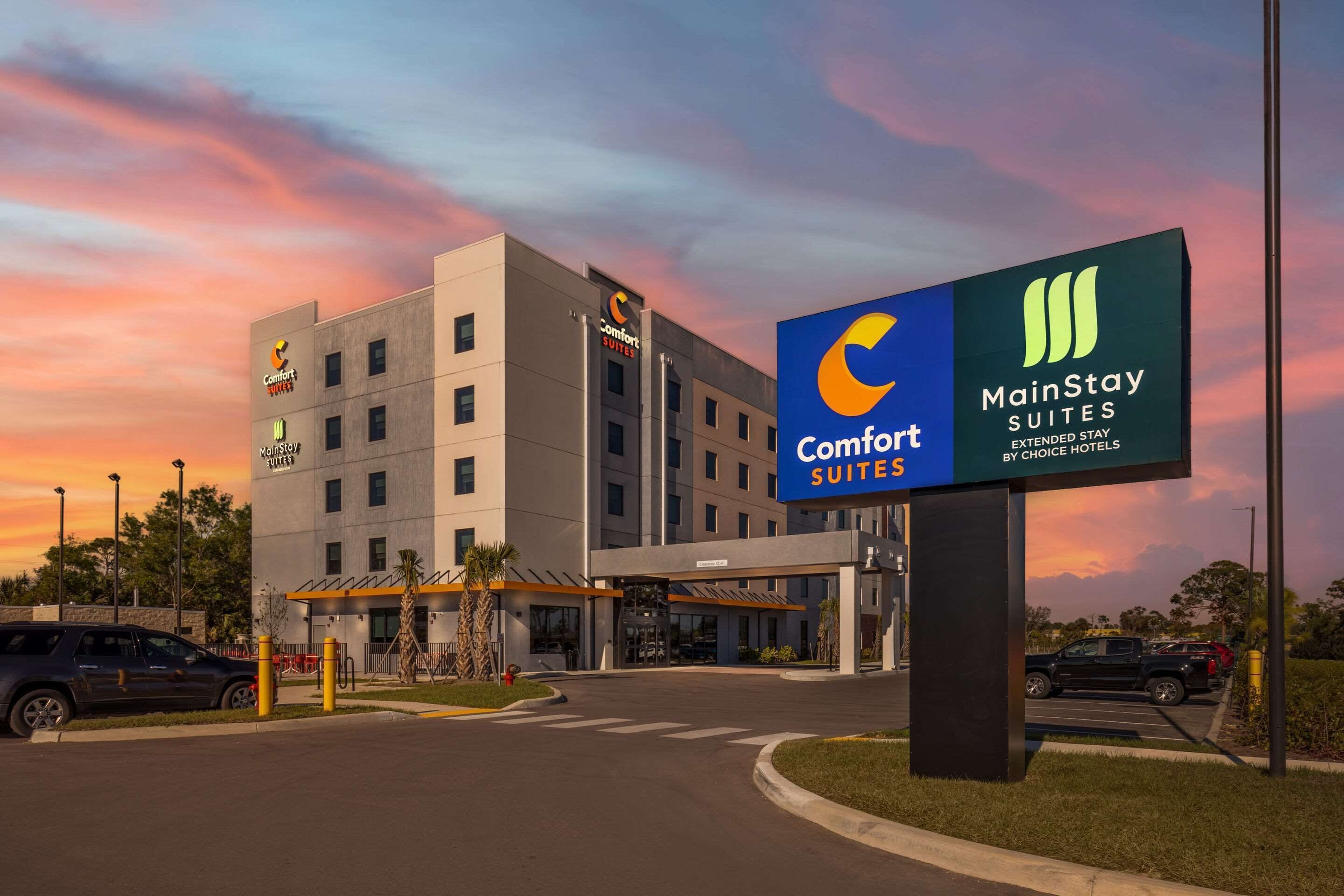 A hotel with a sign for Comfort Suites and MainStay Suites, featuring a modern building and a parking lot.