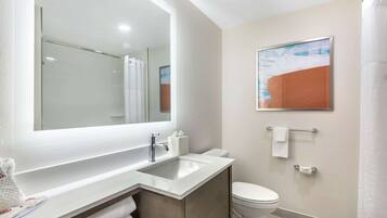 A modern bathroom with a large mirror, a sink, a toilet, and a shower curtain.