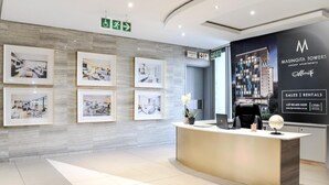 Una moderna zona de recepción con fotografías enmarcadas en la pared, un mostrador de recepción y un gran anuncio de Masingita Towers.