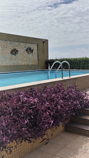 Relax by the pool surrounded by lush greenery and a beautiful mosaic design.
