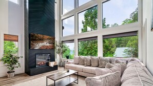 A modern living room with a fireplace, large windows, and a cozy sofa.