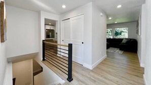 A modern interior with a staircase, wooden flooring, white walls, and a kitchen area. - Airy Modern Farmhouse 5BR/3BA Oasis w/ Fast Wi-Fi (Kent)
