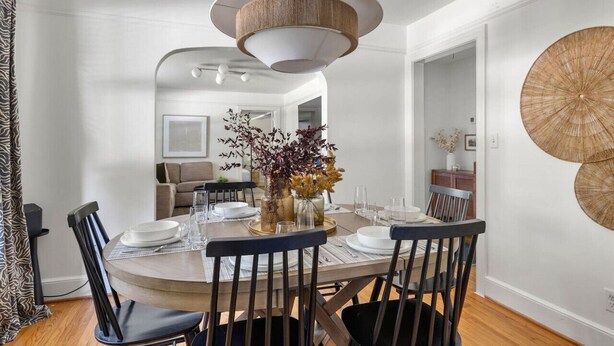 A dining area with a round table set for four, surrounded by black chairs. A large, circular woven light fixture hangs from the ceiling. - Park Circle - Firefly - Renovated 3 Bedroom! (North Charleston)