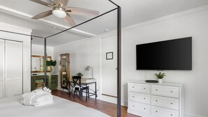 A bedroom with a bed, a desk, a chair, a dresser, a TV, and a ceiling fan. - Park Circle - Firefly - Renovated 3 Bedroom! (North Charleston)