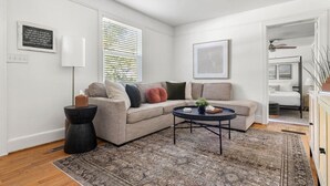 A modern living room with a beige sectional sofa, a round coffee table, and a patterned rug. - Park Circle - Firefly - Renovated 3 Bedroom! (North Charleston)