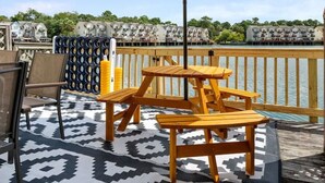 Un terrazza in legno con un tappeto decorato, un ombrellone a righe e mobili da esterno.