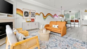 Un soggiorno moderno con divano, tavolino e camino. Sullo sfondo, una cucina con zona pranzo.
