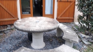 A stone table with benches in a courtyard, surrounded by a stone floor and a wooden fence. - 2* apartment in the mountains (Luz-Saint-Sauveur)