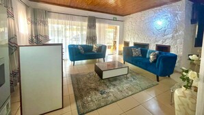 A modern living room with two blue sofas, a coffee table, and a white cabinet. - Mongi Guest House (Harare)