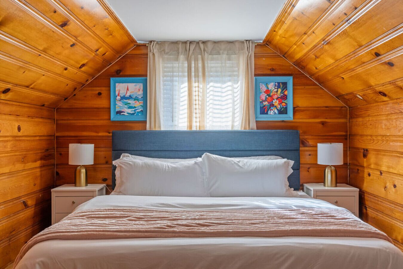 A cozy wooden room with a bed, two bedside tables, and two lamps.