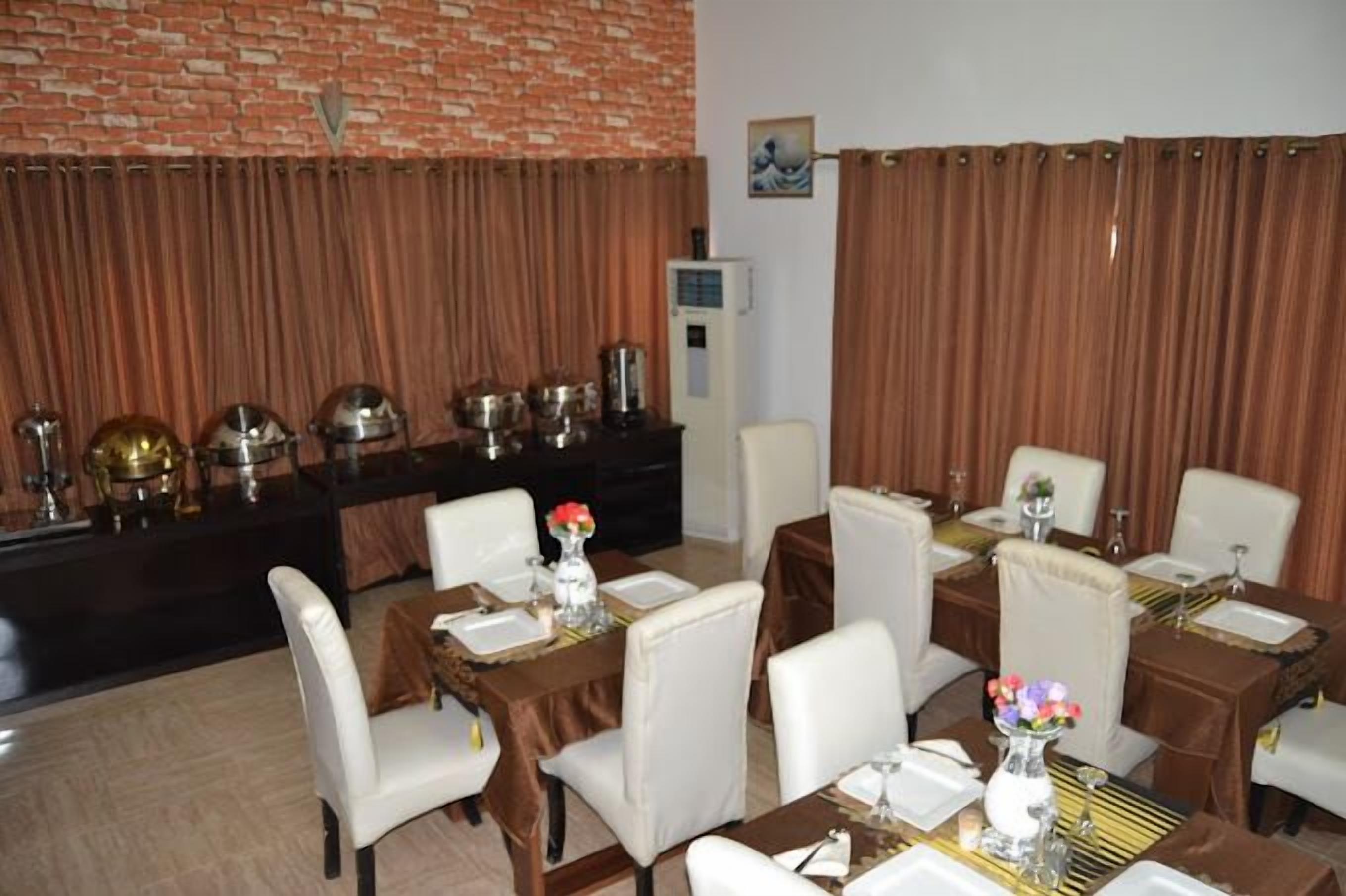 A dining area with multiple tables set for service, a brick wall, and a water dispenser.