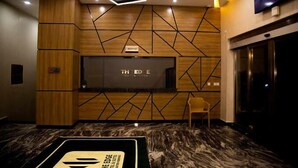 A reception area with a modern design, featuring a wooden panel wall, a flat-screen TV, and a marble floor. - The Edge Hotel and Suites (Abuja)