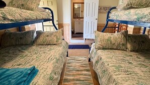 A room with bunk beds, a rug, and a door leading to a bathroom. - Waterfront Bunkroom sits on the Colorado river. (Matagorda)