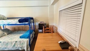 A dorm-style room with two bunk beds, a wooden desk, and a chair. - Waterfront Bunkroom sits on the Colorado river. (Matagorda)