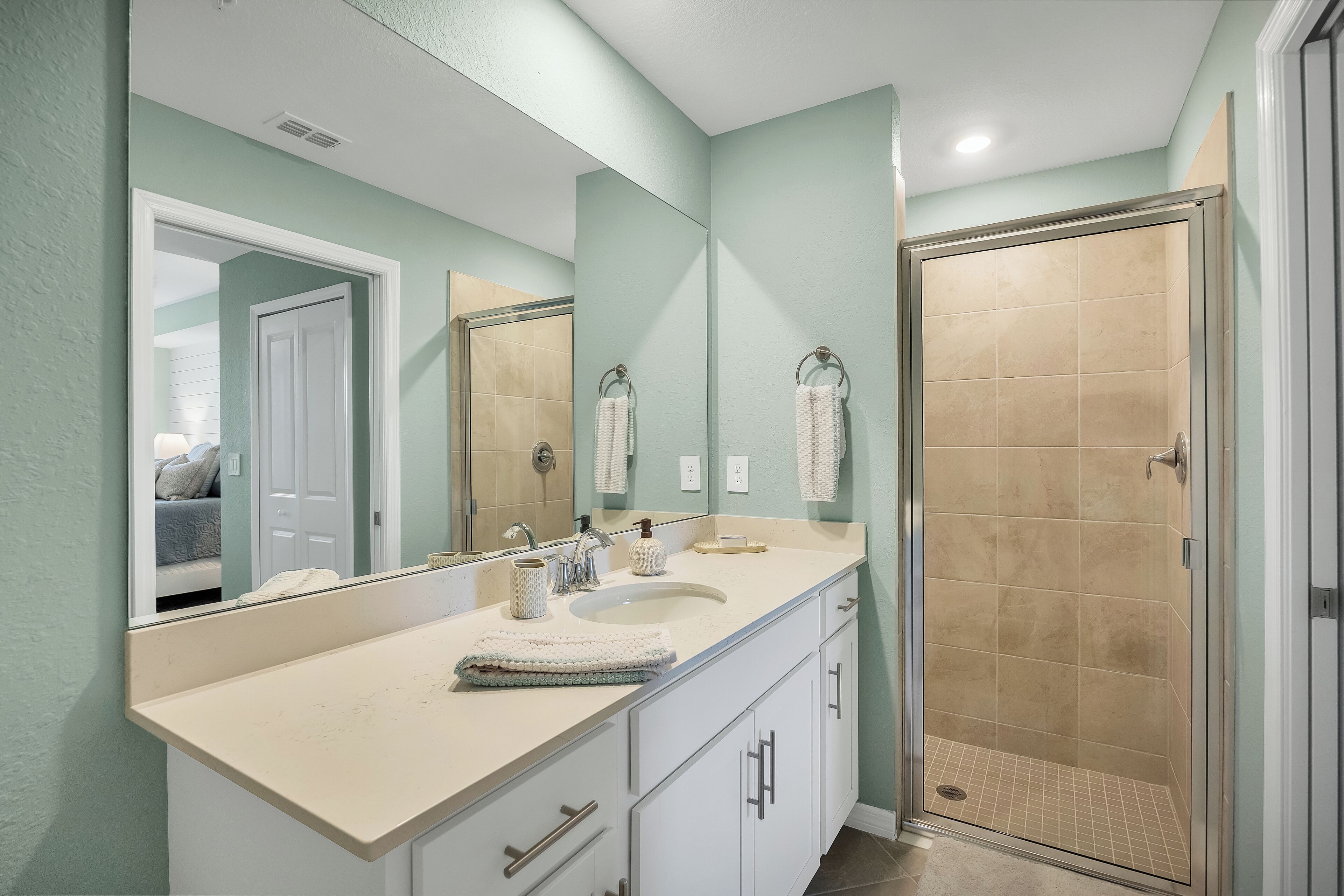 A bathroom with a large mirror, a sink, and a shower.