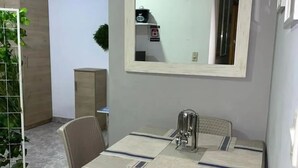 Een eetgedeelte met een tafel, stoelen en een grote spiegel aan de wand.