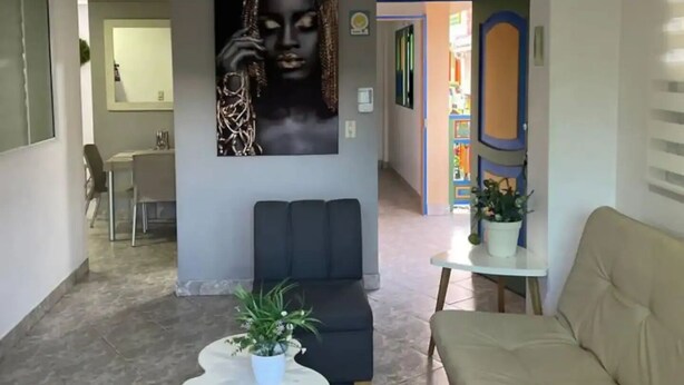 Een moderne woonkamer met een groot abstract schilderij, een blauwe bank, een beige bank en een witte salontafel met een plant.