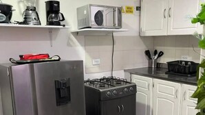 Een keuken met een koelkast, fornuis, magnetron en koffiezetapparaat.