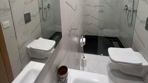 A modern bathroom with a glass-enclosed shower, a white toilet, and a bathtub. - Appart ô atlas Guéliz (Marrakech)