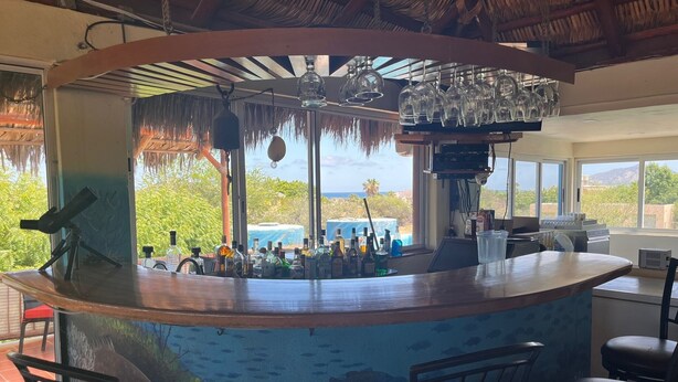 A bar area with a view of the ocean, bar stools, and a ceiling fan. - Cabo Pulmo Beach Resort (Cabo Pulmo)