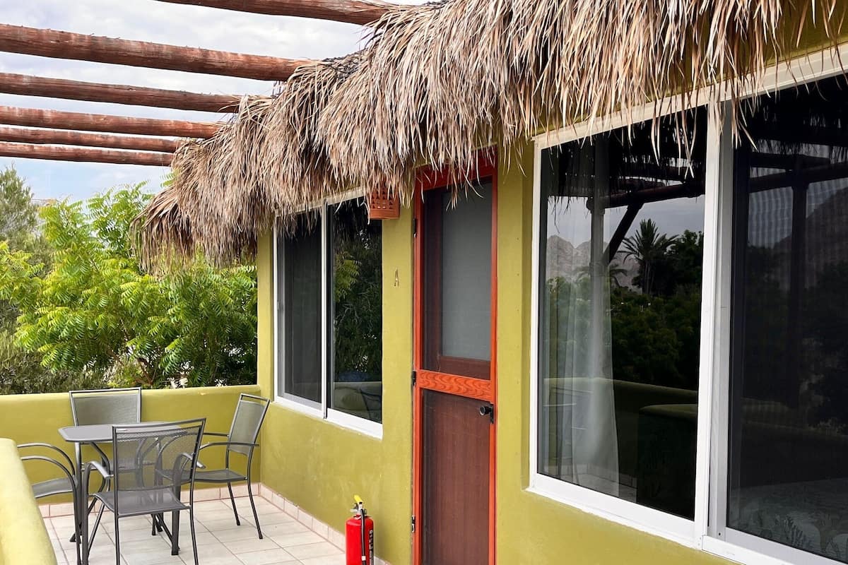 A room with a thatched roof, large windows, and a fire extinguisher on the floor.