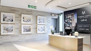 Una moderna zona de recepción con fotografías enmarcadas en la pared, un mostrador de recepción y un gran anuncio de Masingita Towers.