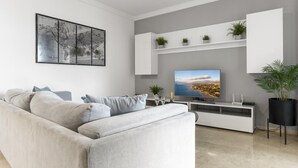 A modern living room with a grey sofa, a flat-screen TV, and a world map artwork on the wall. - Apartment in Terrazas de Banús for 4 people | 13-4-1 (Puerto Banús - Marbella)