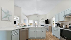 A spacious kitchen with a large island, white cabinetry, and modern appliances. - Coastal Charm, Private Pool, Private Beach Access! (Destin)