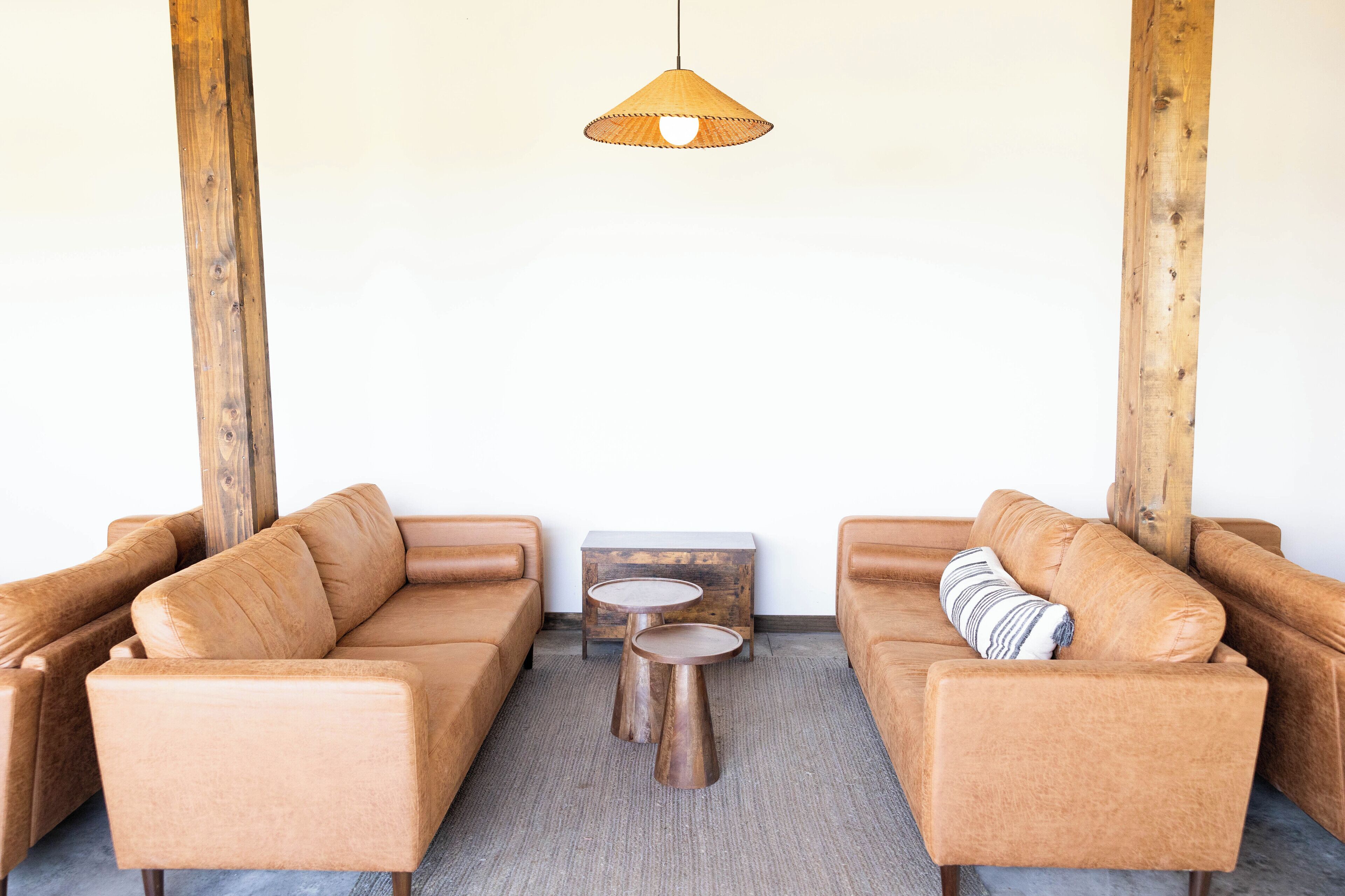 A modern living room with two brown sofas, a small wooden coffee table, and a hanging light fixture.