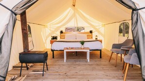 Ein Zeltraum mit Bett, Tisch und zwei Stühlen.