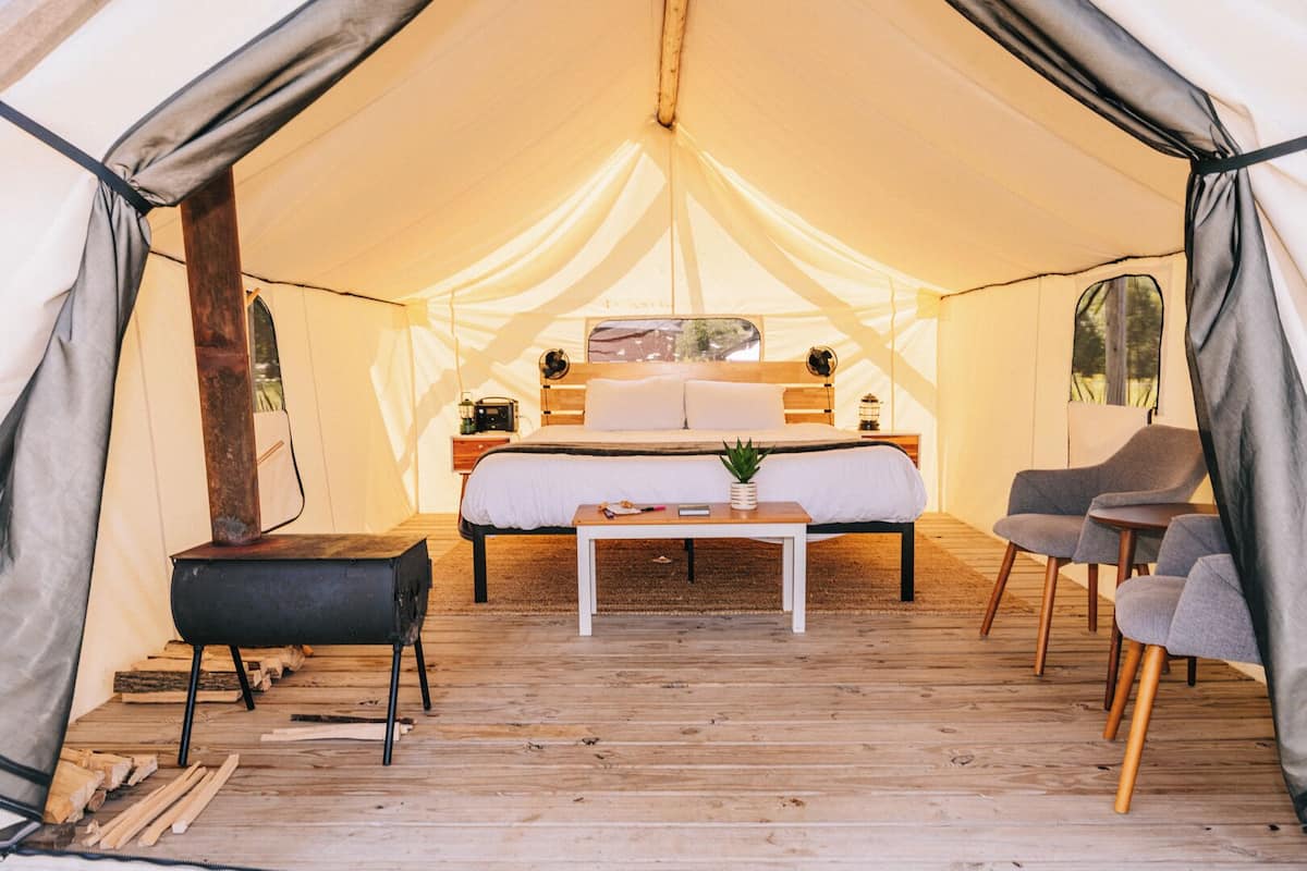 Ein Zeltraum mit Bett, Tisch und zwei Stühlen.