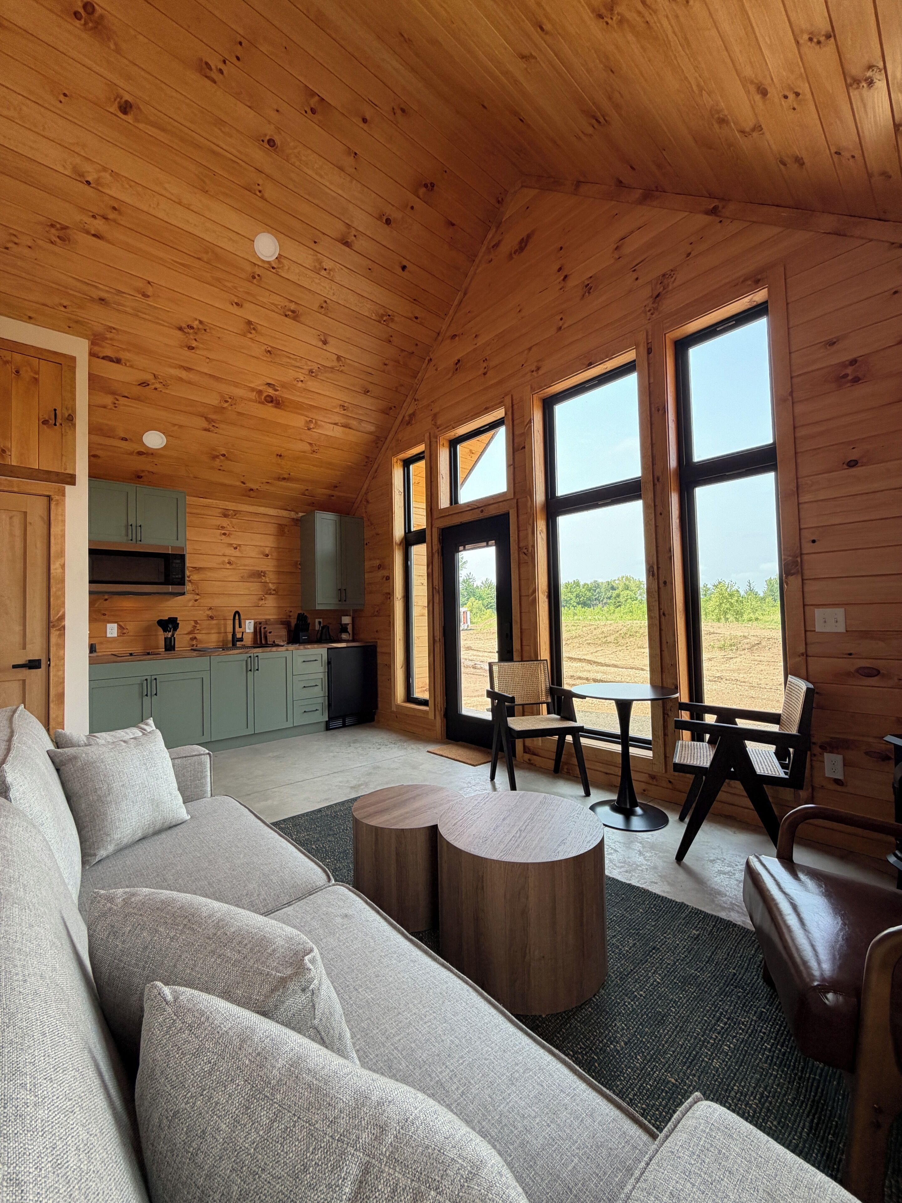 L’intérieur chaleureux d’un chalet avec un plafond en bois, un canapé, une table à manger et un coin cuisine.