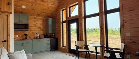 Interior acogedor de una cabaña con techo de madera, un sofá, una mesa de comedor y una zona de cocina.