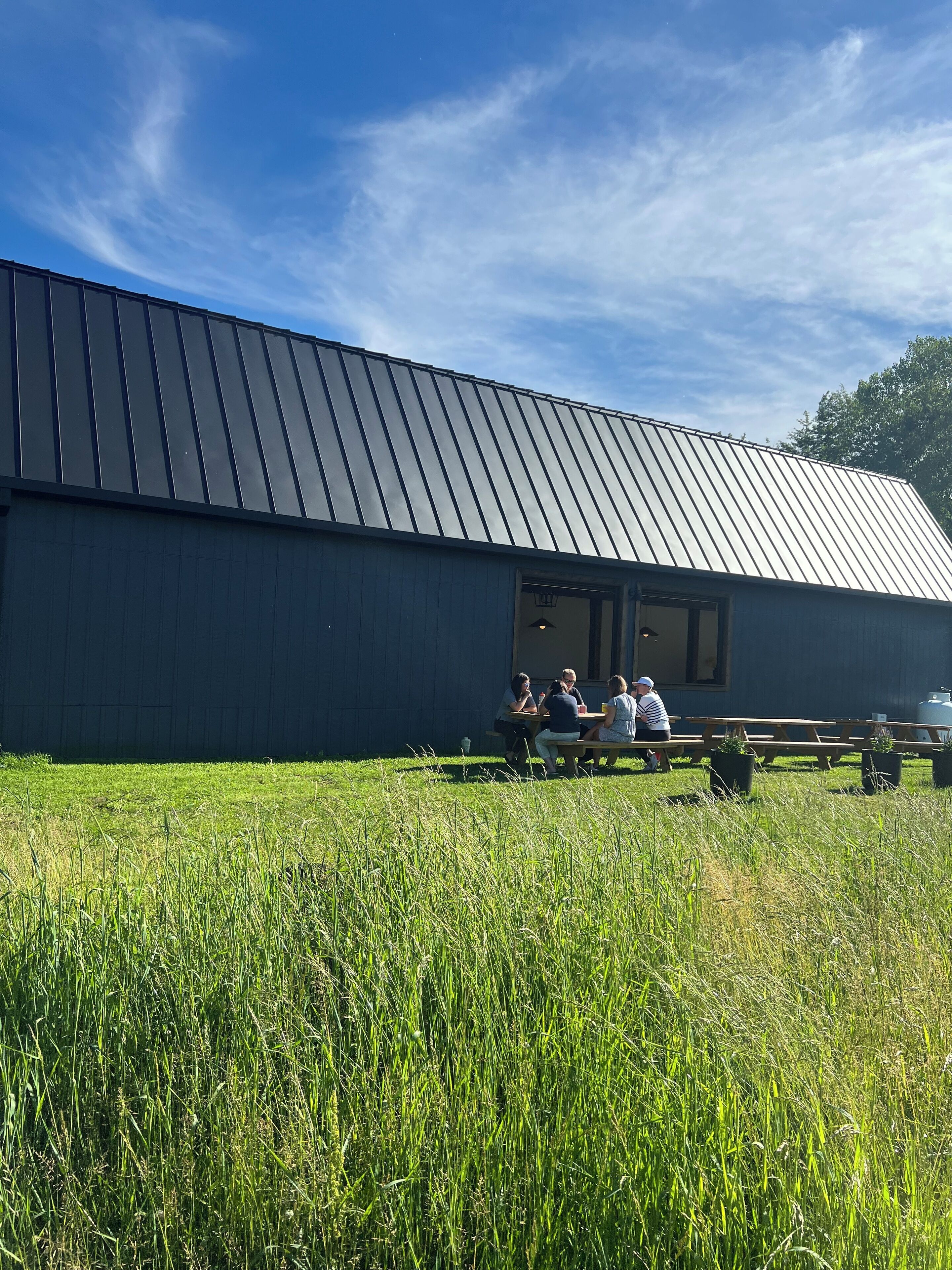 A building with a metal roof and a large open area with picnic tables.