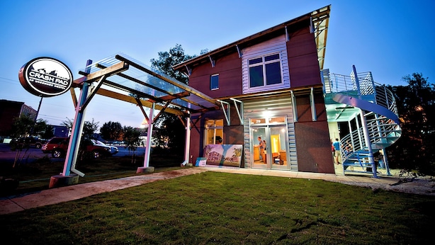 Um edifício com uma placa que diz "CRASH PAD" e uma escadaria em espiral que leva à entrada.