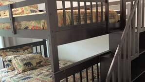 A bunk bed with a wooden frame and a quilted bedspread featuring animal prints.