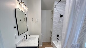 Ein modernes Badezimmer mit einem weißen Waschtisch, einem großen Spiegel und einer Dusche mit sechseckischen Fliesen.