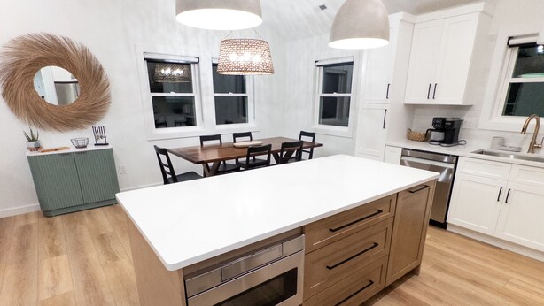 A modern kitchen with a central island, white cabinets, and a wooden floor. - Brand New Home Family-friendly Nags Head, NC OBX 4 BR 3 BA (Nags Head)