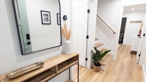 A hallway with a wooden console table, a large mirror, and a potted plant. - Brand New Home Family-friendly Nags Head, NC OBX 4 BR 3 BA (Nags Head)