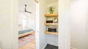 A hallway with a bed, a ceiling fan, and shelves with baskets and a plant. - Brand New Home Family-friendly Nags Head, NC OBX 4 BR 3 BA (Nags Head)
