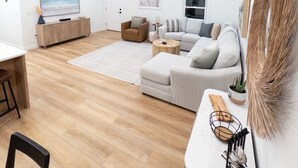 A spacious living room with a large sofa, a coffee table, and a dining area with a table and chairs. - Brand New Home Family-friendly Nags Head, NC OBX 4 BR 3 BA (Nags Head)