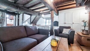 Un intérieur chaleureux avec un plafond en bois, un canapé, un fauteuil et une table en bois.