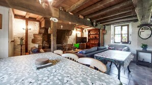 Une pièce rustique avec un plafond en bois, un mur en pierre, une cheminée, un téléviseur et un canapé.