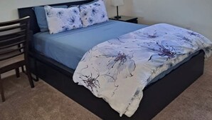 Ein Schlafzimmer mit Bett, Nachttisch, Stuhl und Fenster.