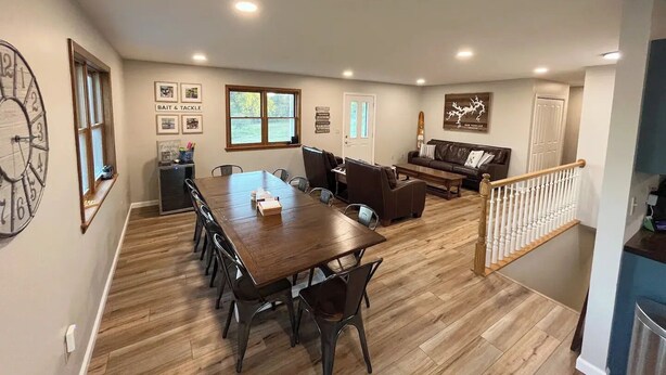 A spacious living area with a large wooden dining table, comfortable seating, and a staircase leading to an upper level.