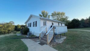 A single-story mobile home with a front porch and a small deck.