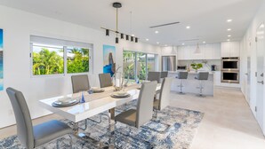 Une cuisine moderne avec des meubles blancs, des appareils en acier inoxydable et un îlot central doté de tabourets de bar.